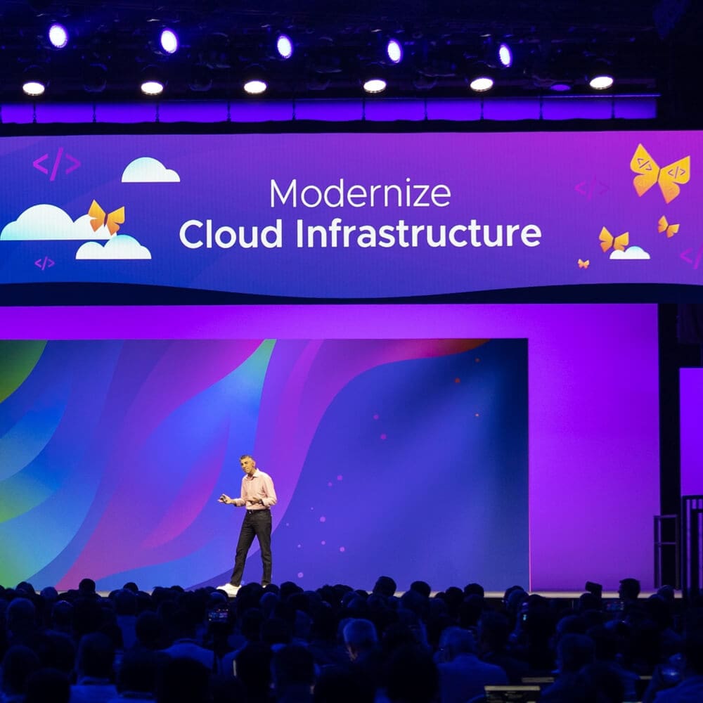 A person in front of a large audience gives a keynote presentation focused on "Modernize Cloud Infrastructure."