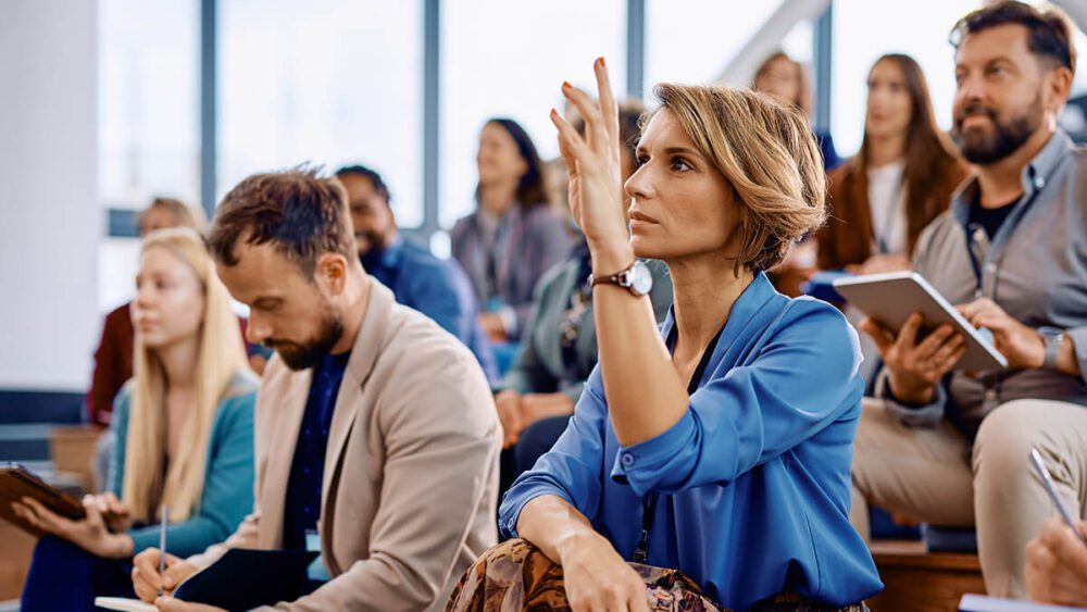 Woman raising her hand during a communication training workshop.